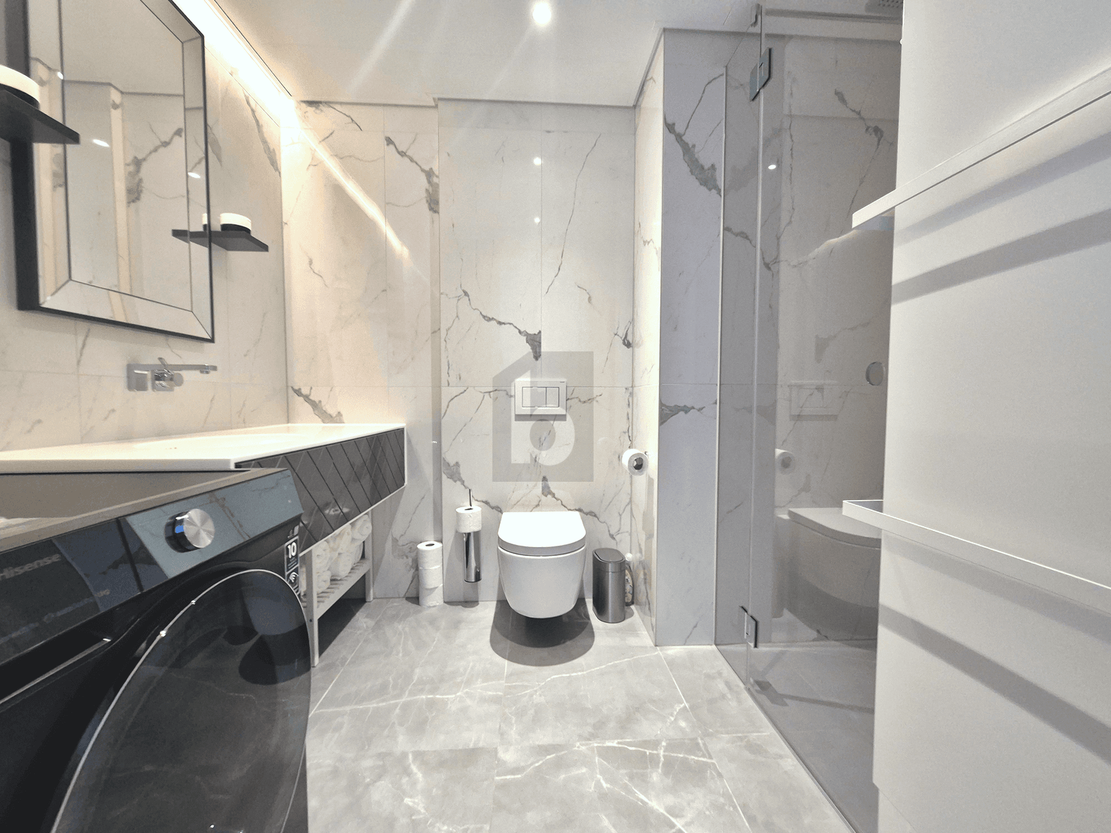 Elegantes Badezimmer mit Marmorfliesen, begehbarer Dusche und integrierter Waschmaschine.