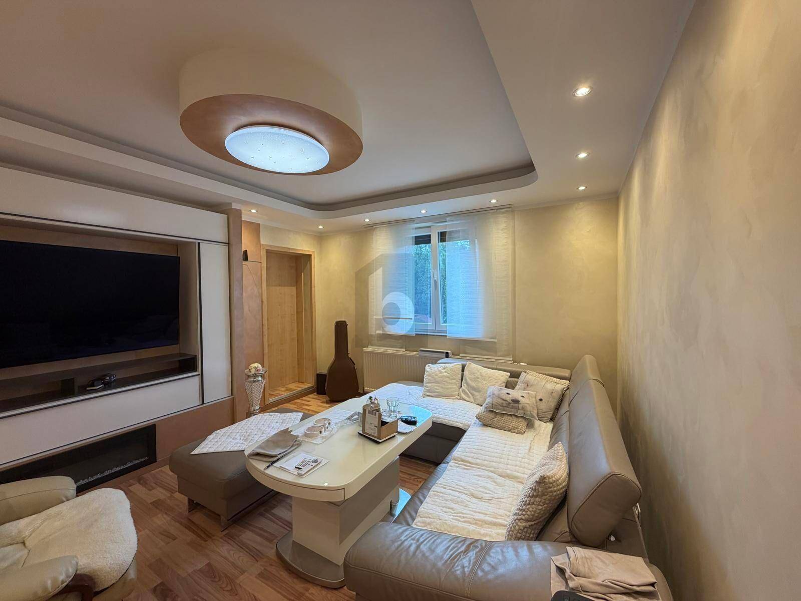 Modernes Wohnzimmer mit bequemer Eckcouch, Fernseher und indirekter Beleuchtung, hell und einladend.