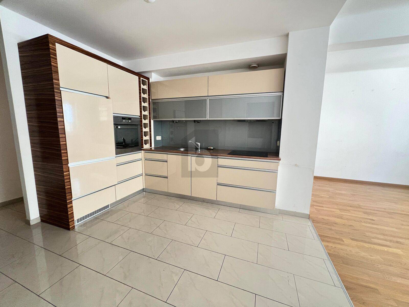 Moderne Einbauküche mit beigen Fronten, integrierten Geräten und Holzakzenten.