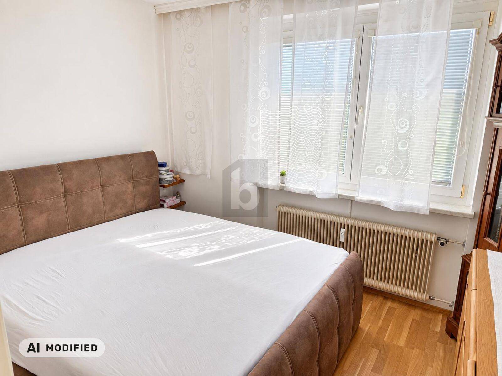 Helles Schlafzimmer mit großem Bett, weißen Wänden und Fenster mit Jalousien.