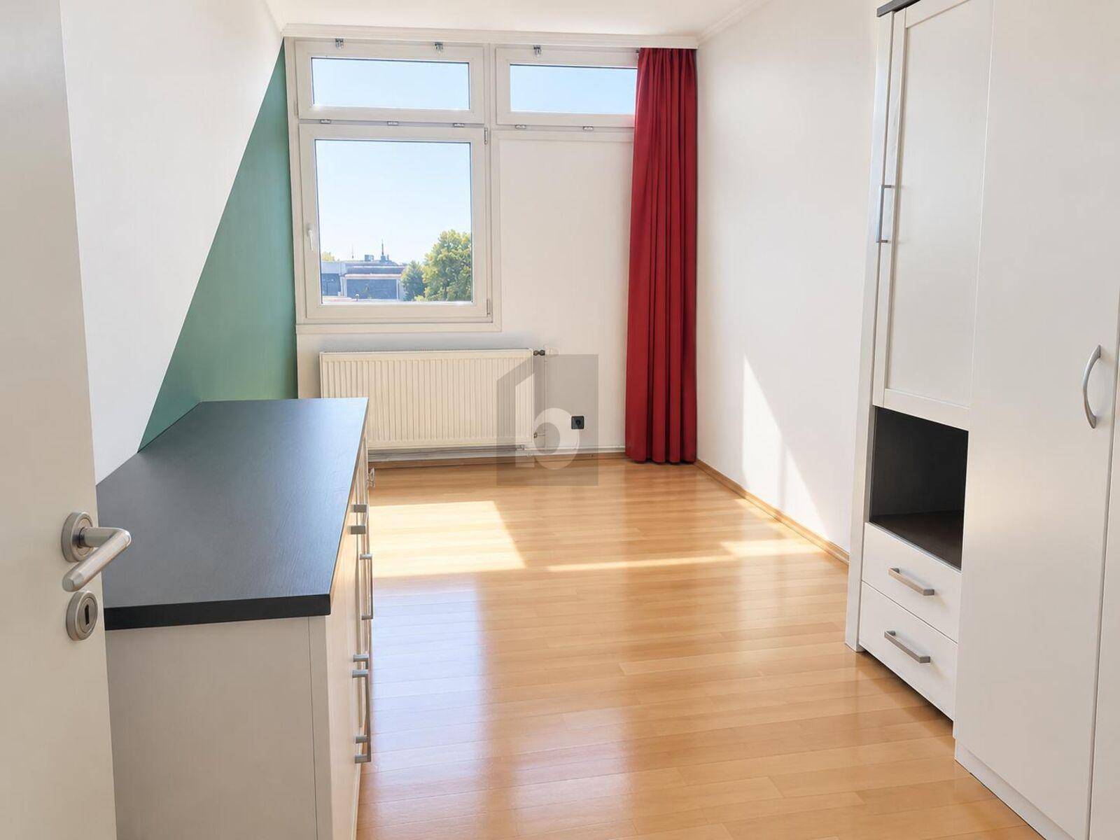 Helles Schlafzimmer mit Holzfußboden, großem Fenster und farbiger Akzentwand.