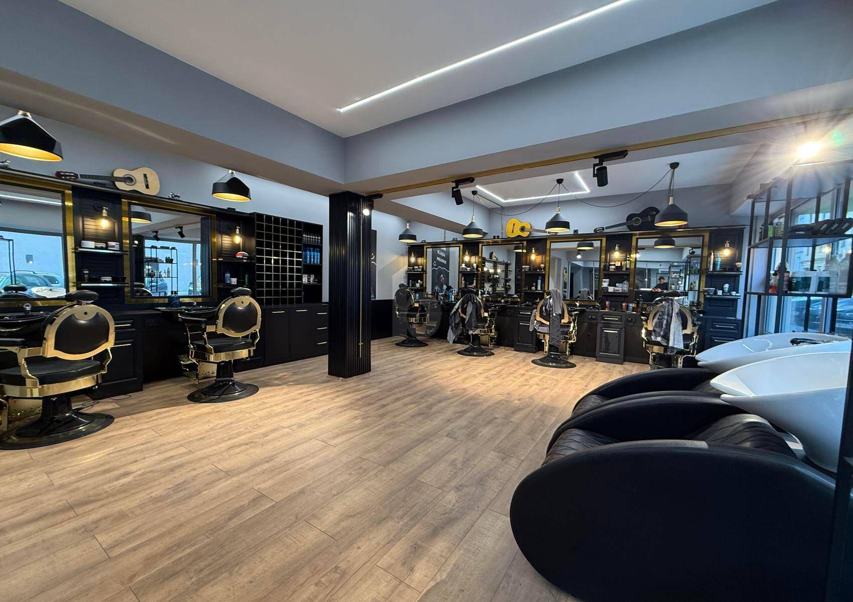 Innenansicht des Friseursalons mit mehreren eleganten Bedienplätzen und großen Spiegeln.