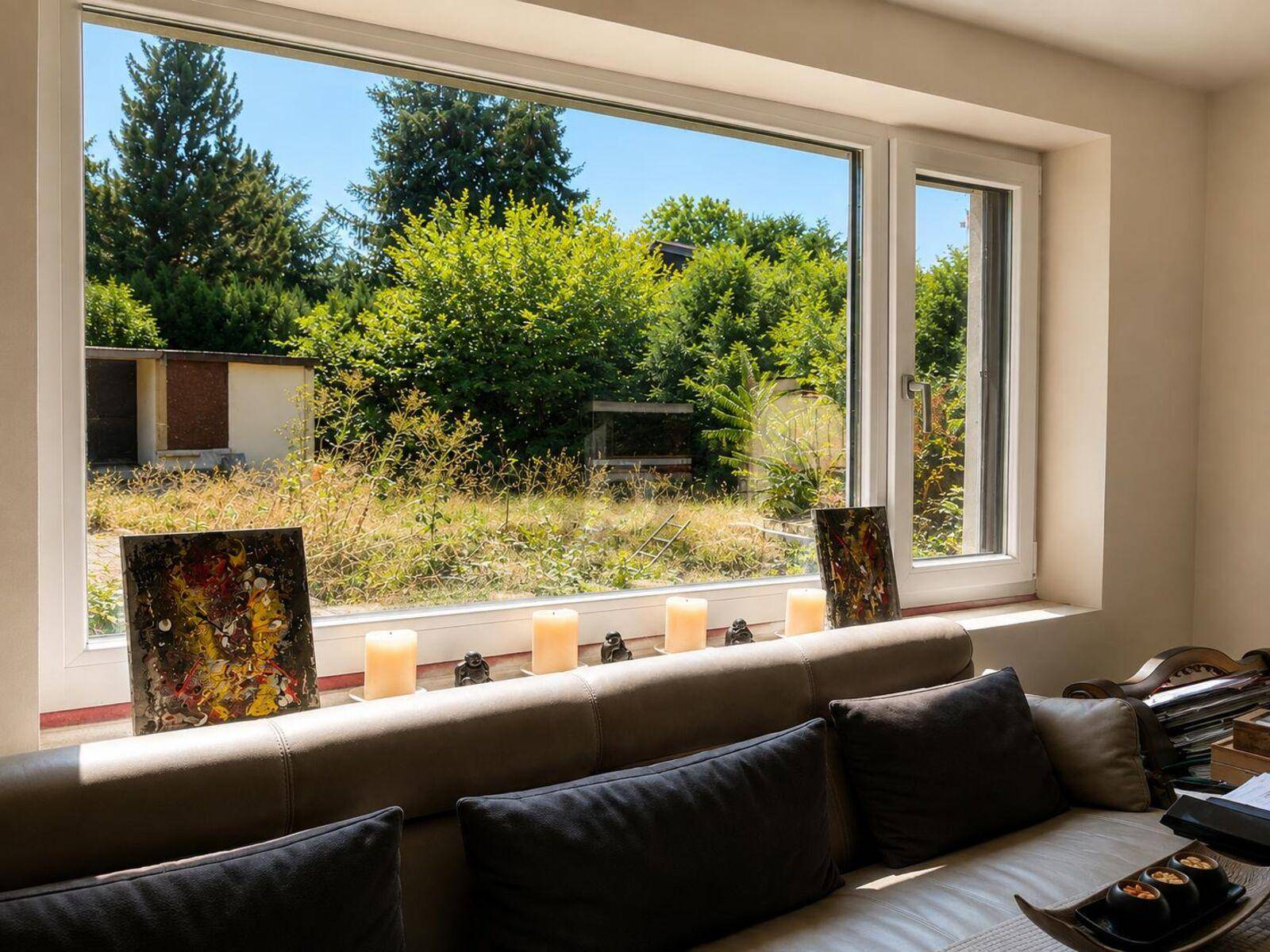 Helles Wohnzimmer mit großem Fenster und Blick ins Grüne.