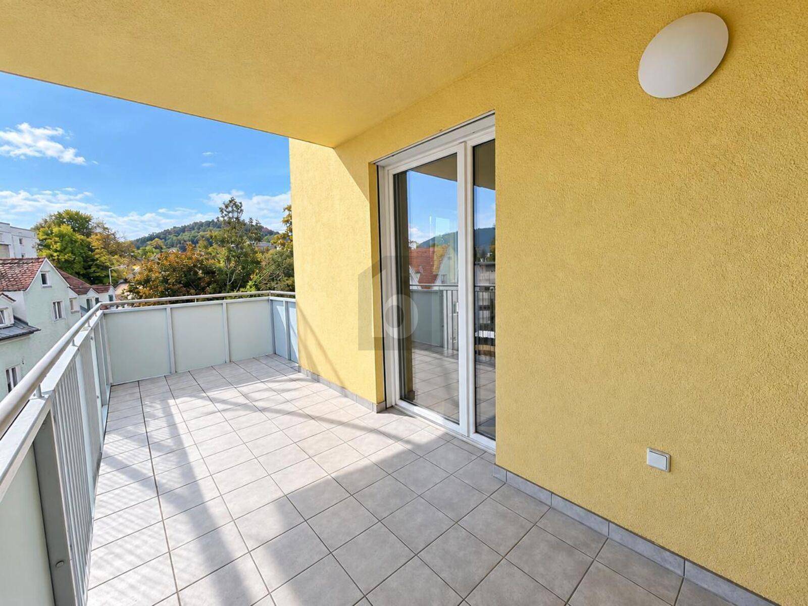 Geräumiger Balkon mit Fliesenboden und schöner Aussicht ins Grüne.