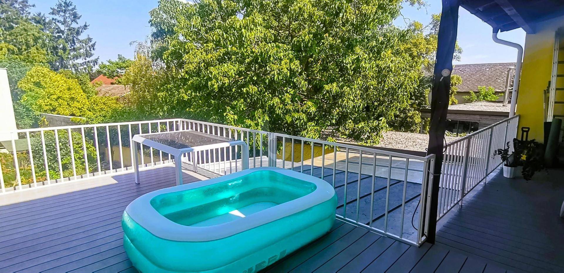 Sonnige Terrasse mit aufblasbarem Pool und Blick ins Grüne.