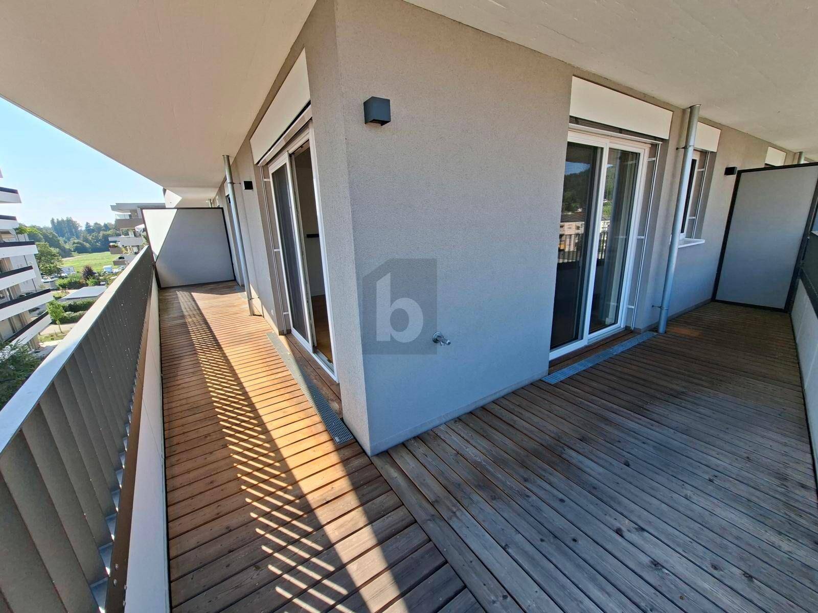 Geräumiger Balkon mit Holzboden und moderner Architektur, ideal für entspannte Stunden im Freien.
