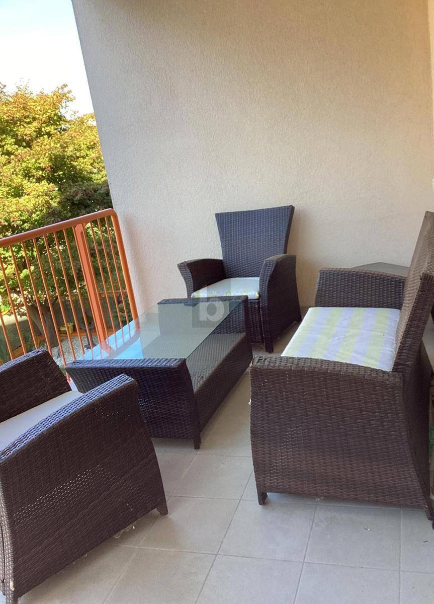 Gemütlicher Balkon mit Rattanmöbeln und Blick ins Grüne, ideal für entspannte Stunden im Freien.