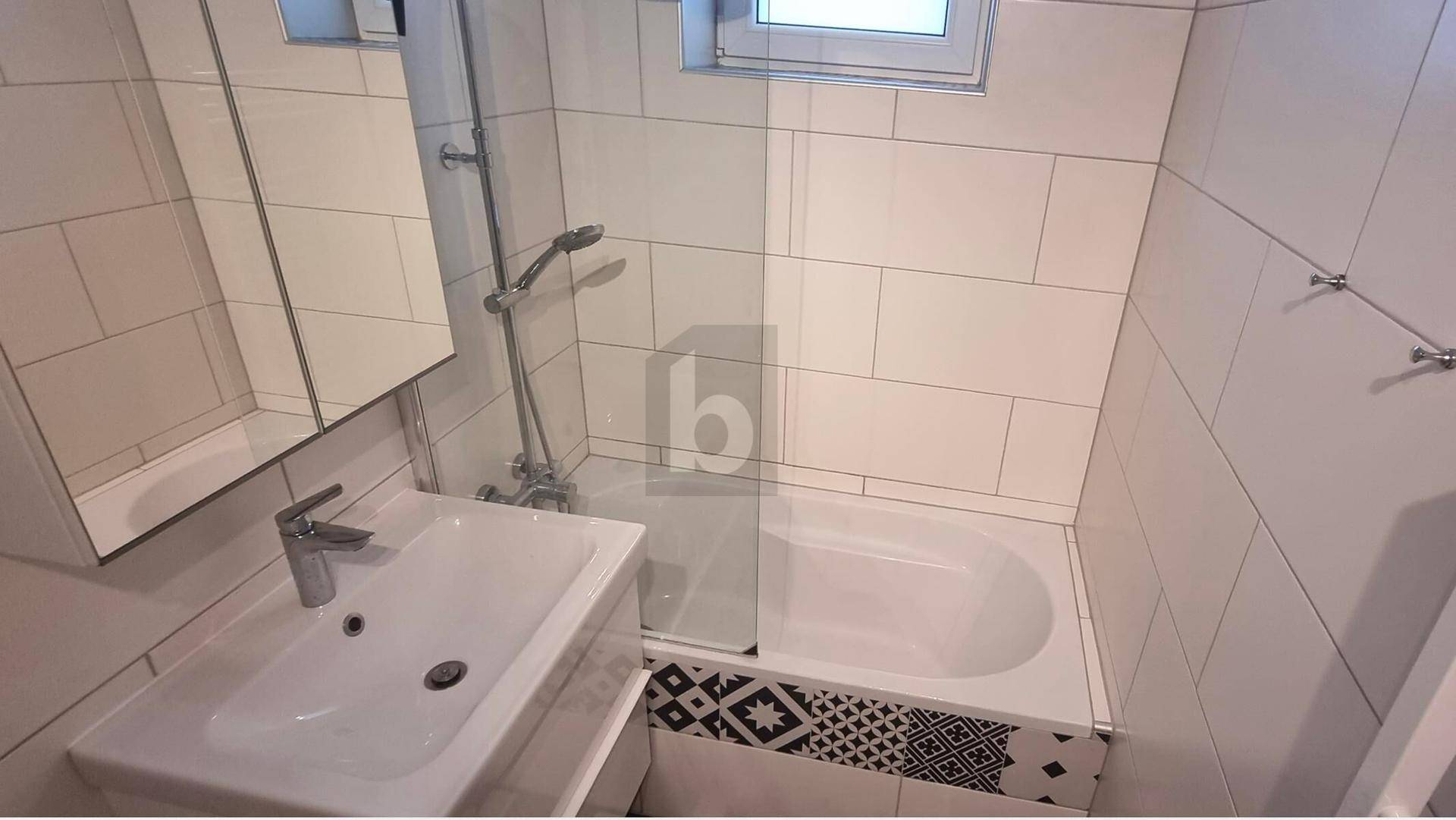 Modernes Badezimmer mit Badewanne, Dusche, Waschbecken und einem Fenster für Tageslicht.