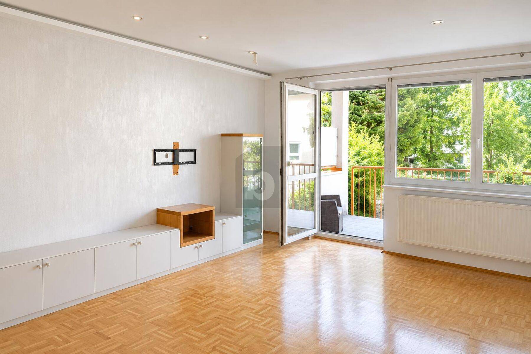 Helles Wohnzimmer mit Parkettboden, einem modernen Sideboard und Zugang zu einem Balkon.