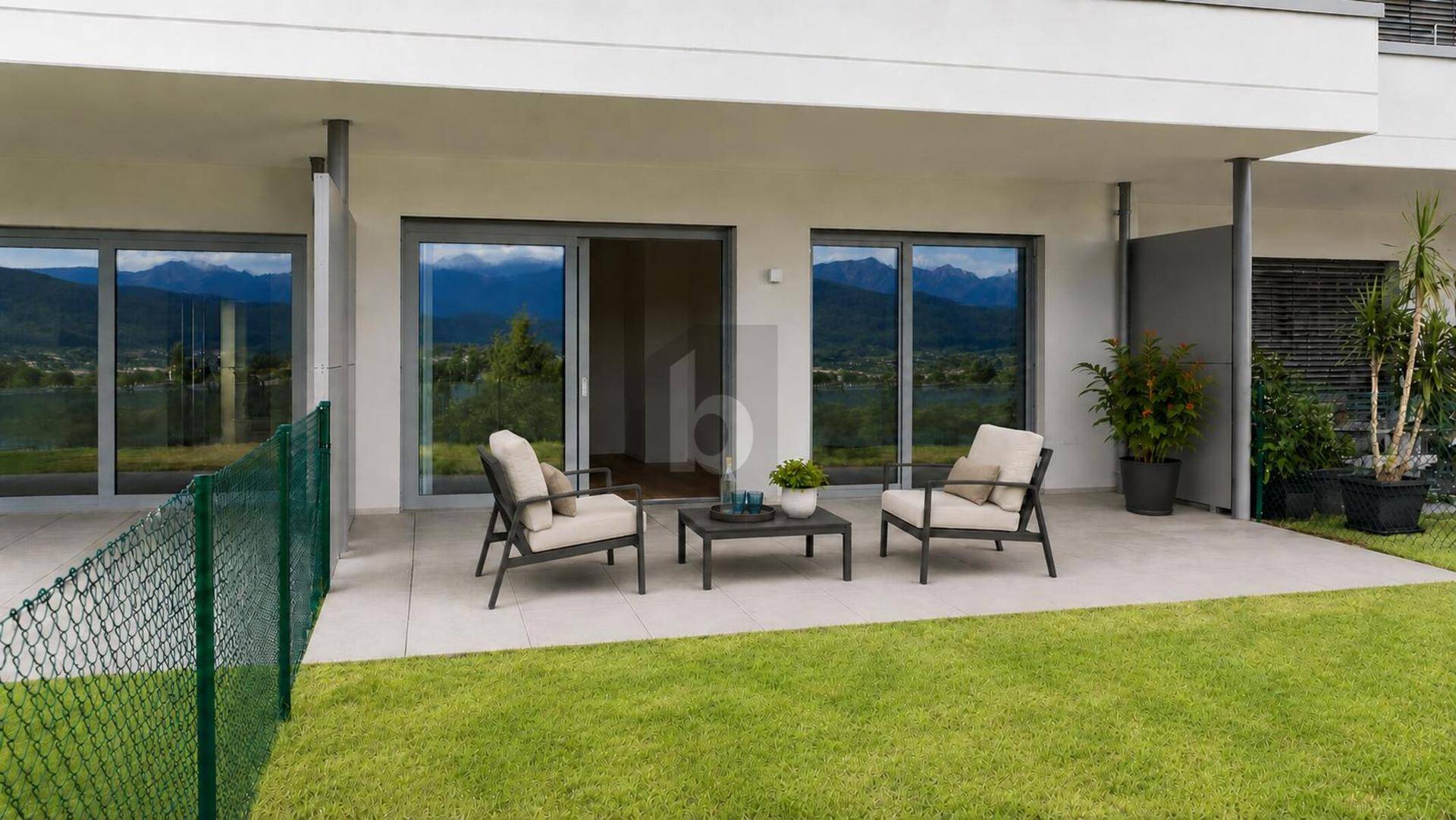 Möblierte Terrasse mit Sitzgelegenheiten und Blick auf die grüne Landschaft und Berge.