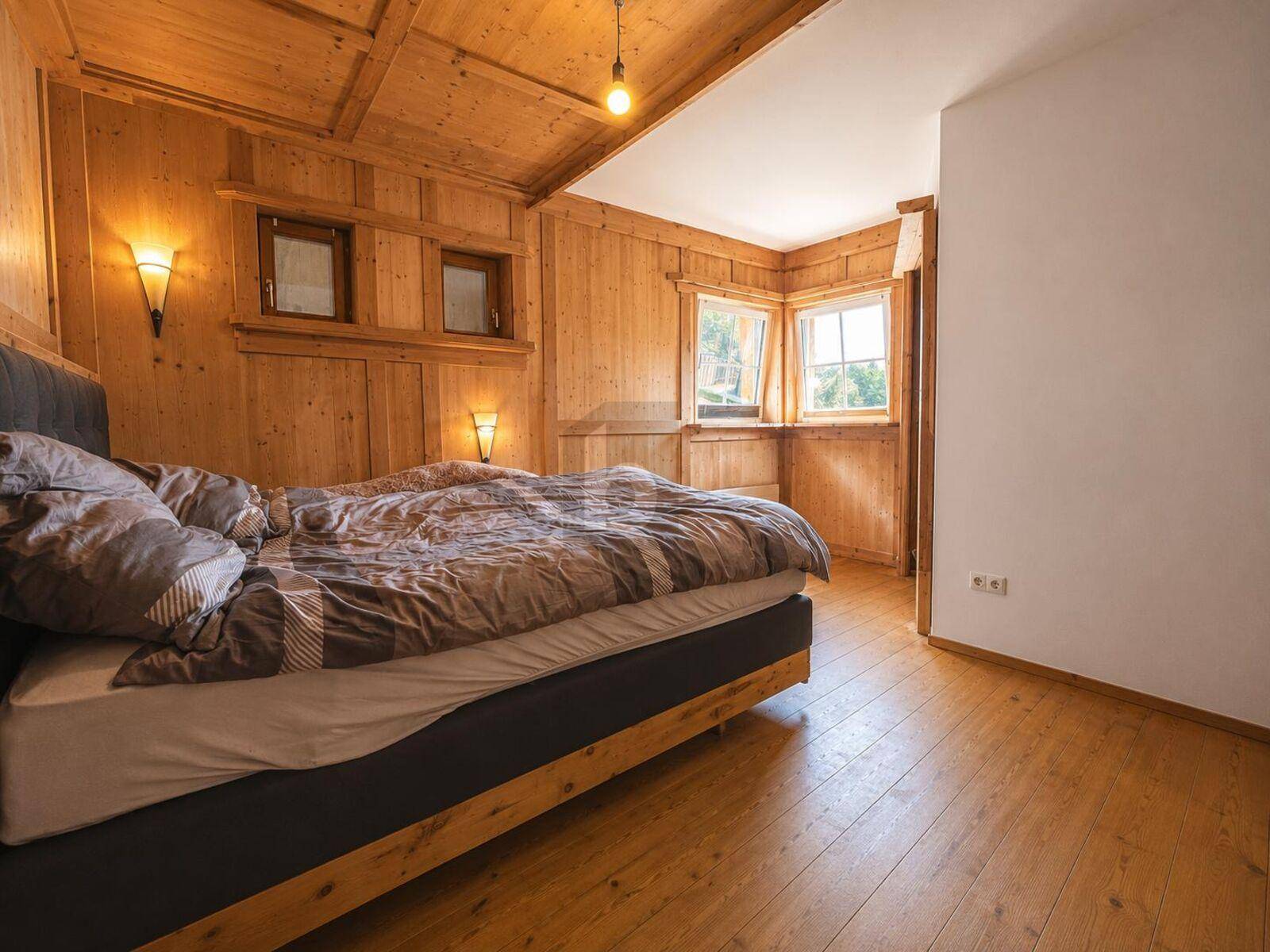 Schlafzimmer mit großem Bett, Holzwänden und Holzdecke, bietet eine warme Atmosphäre.