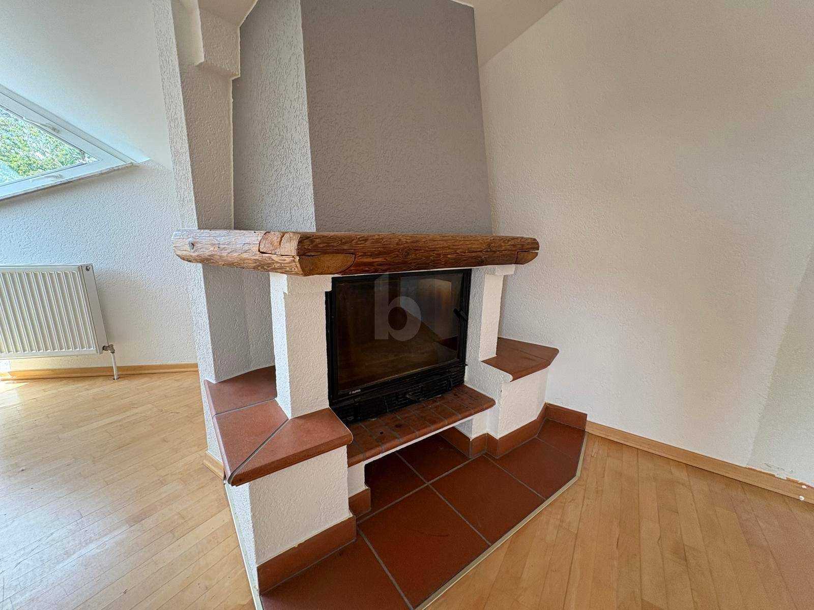 Detailansicht eines rustikalen Kamins mit Holzbalken und Terrakotta-Akzenten im Wohnbereich.