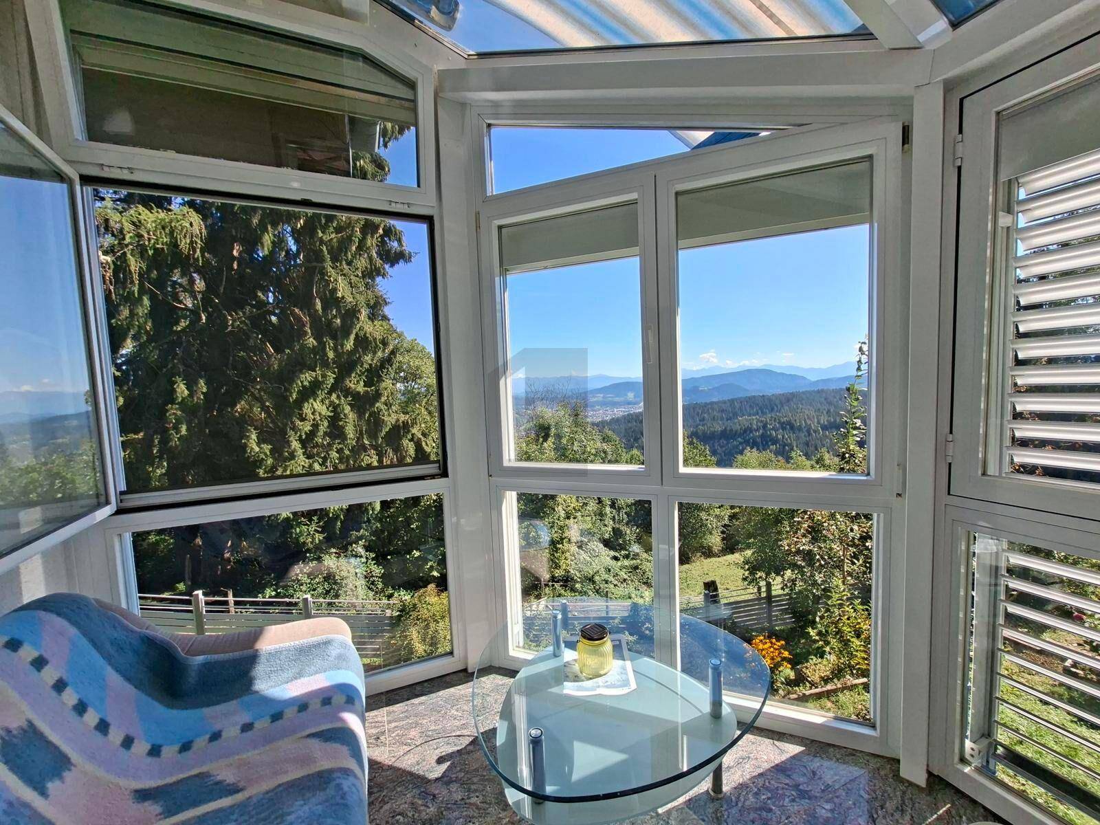 Heller Wintergarten mit Panoramablick auf die Berge und die umliegende grüne Landschaft.