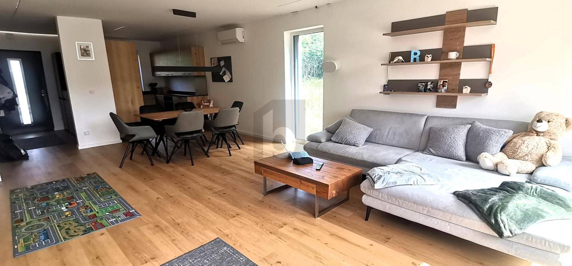 Heller, offener Wohn- und Essbereich mit Holzboden, gemütlichem Sofa und modernem Esstisch.