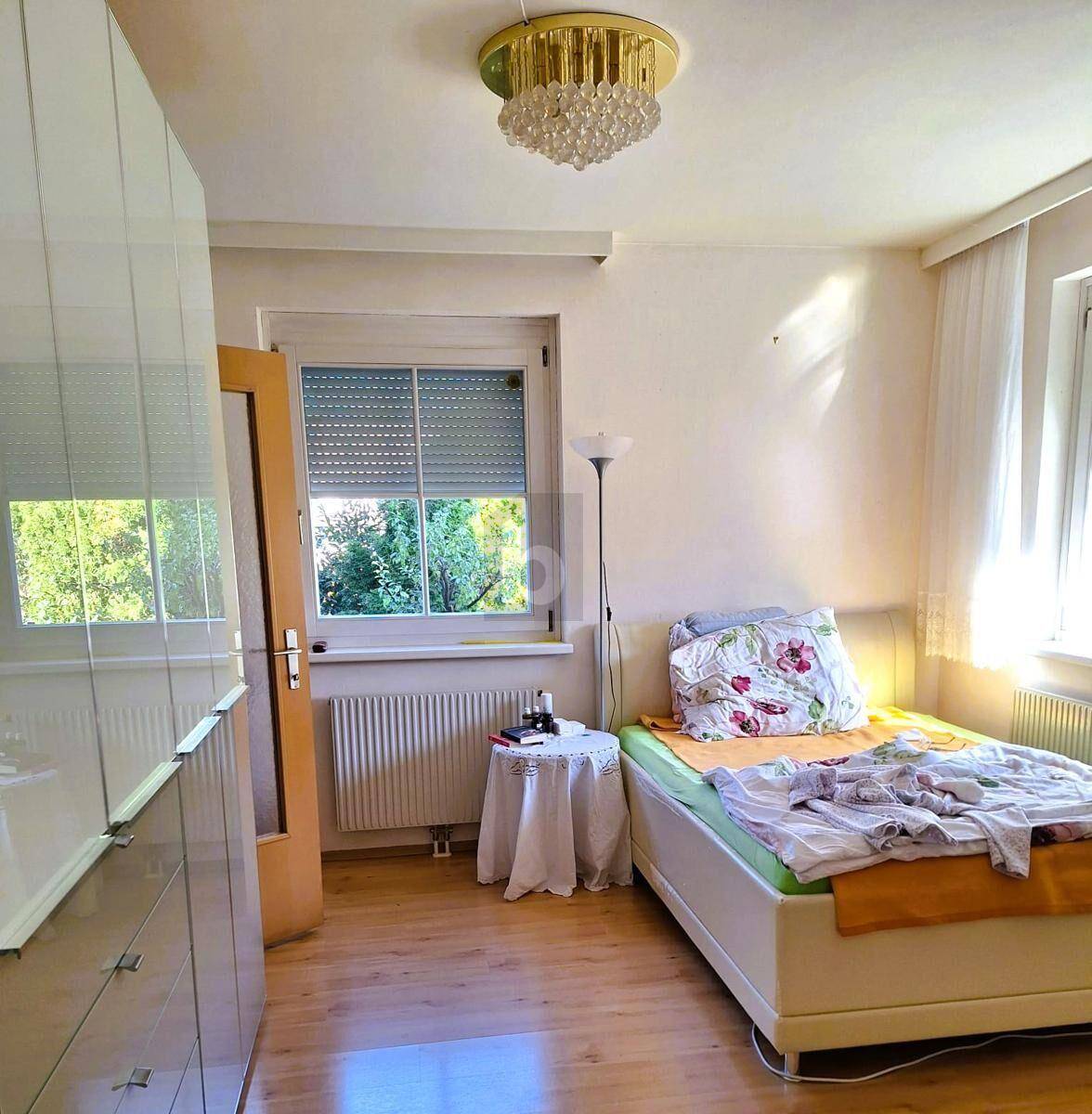 Helles Schlafzimmer mit Einzelbett, Holzfußboden und großem Kleiderschrank.