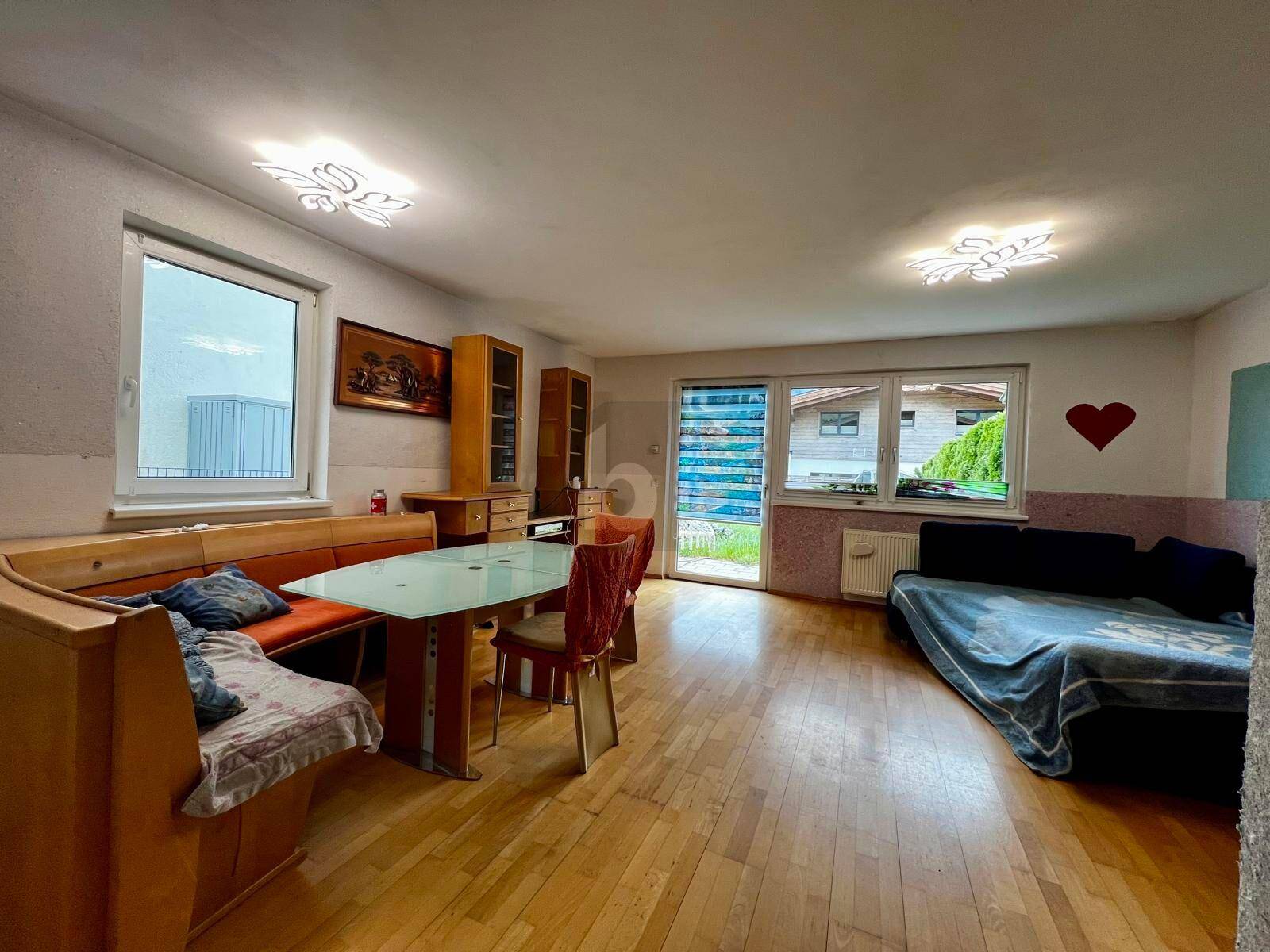 Gemütlicher Wohn-Essbereich mit Holzboden, Eckbank und Sofa, hell durch große Fenster.