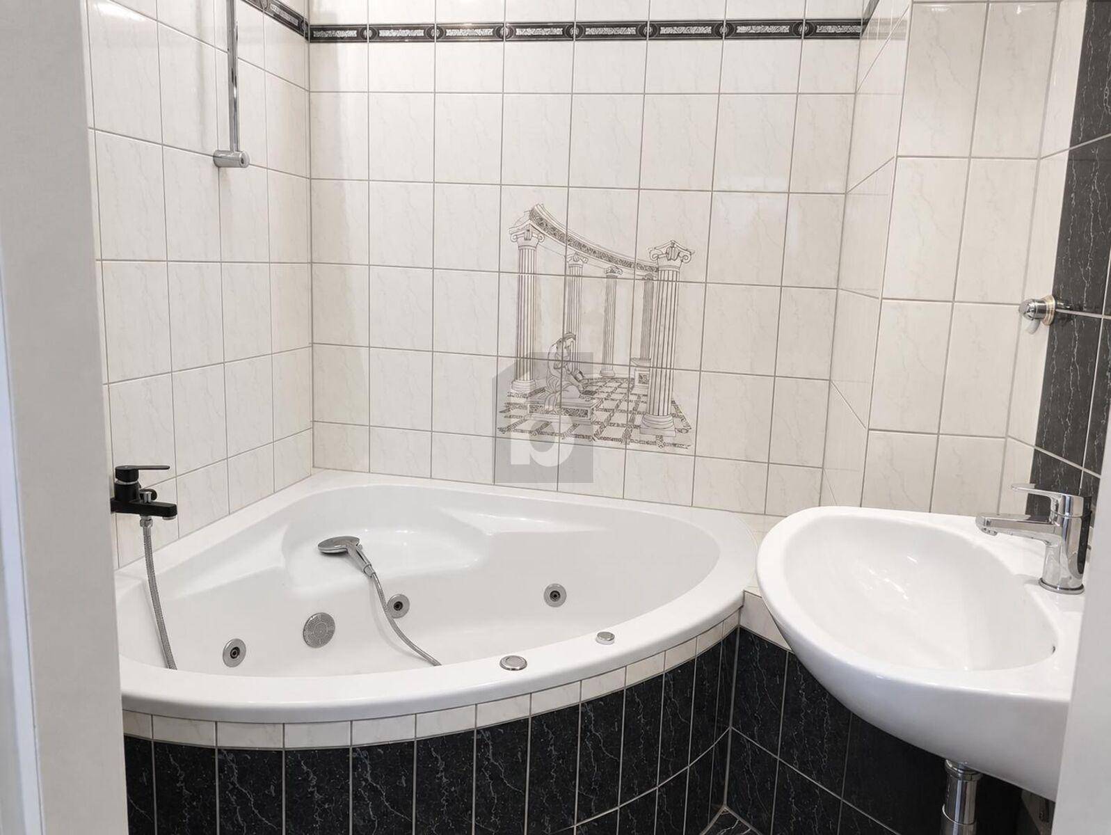 Badezimmer mit Eck-Whirlpool-Badewanne und modernen Fliesen in Schwarz-Weiß.