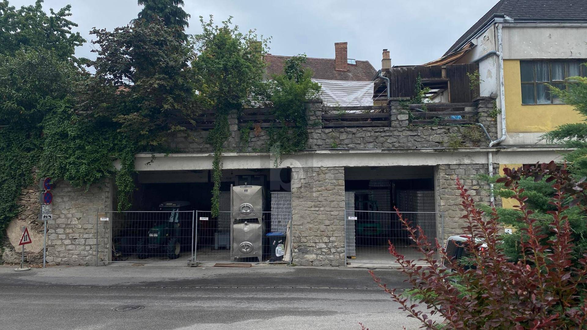 Zwei Garagenzufahrten in einer Steinmauer mit einer darüberliegenden Terrasse im Bau.