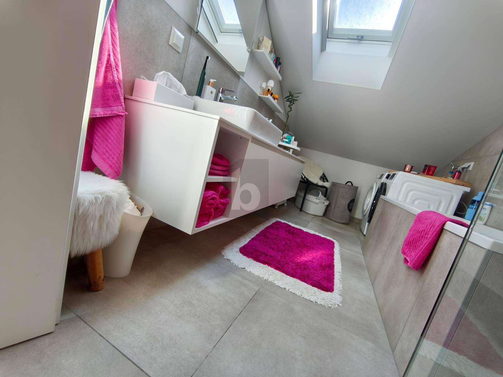 Modernes Badezimmer mit Doppelwaschbecken, Dusche und Dachfenstern unter Schrägdach.