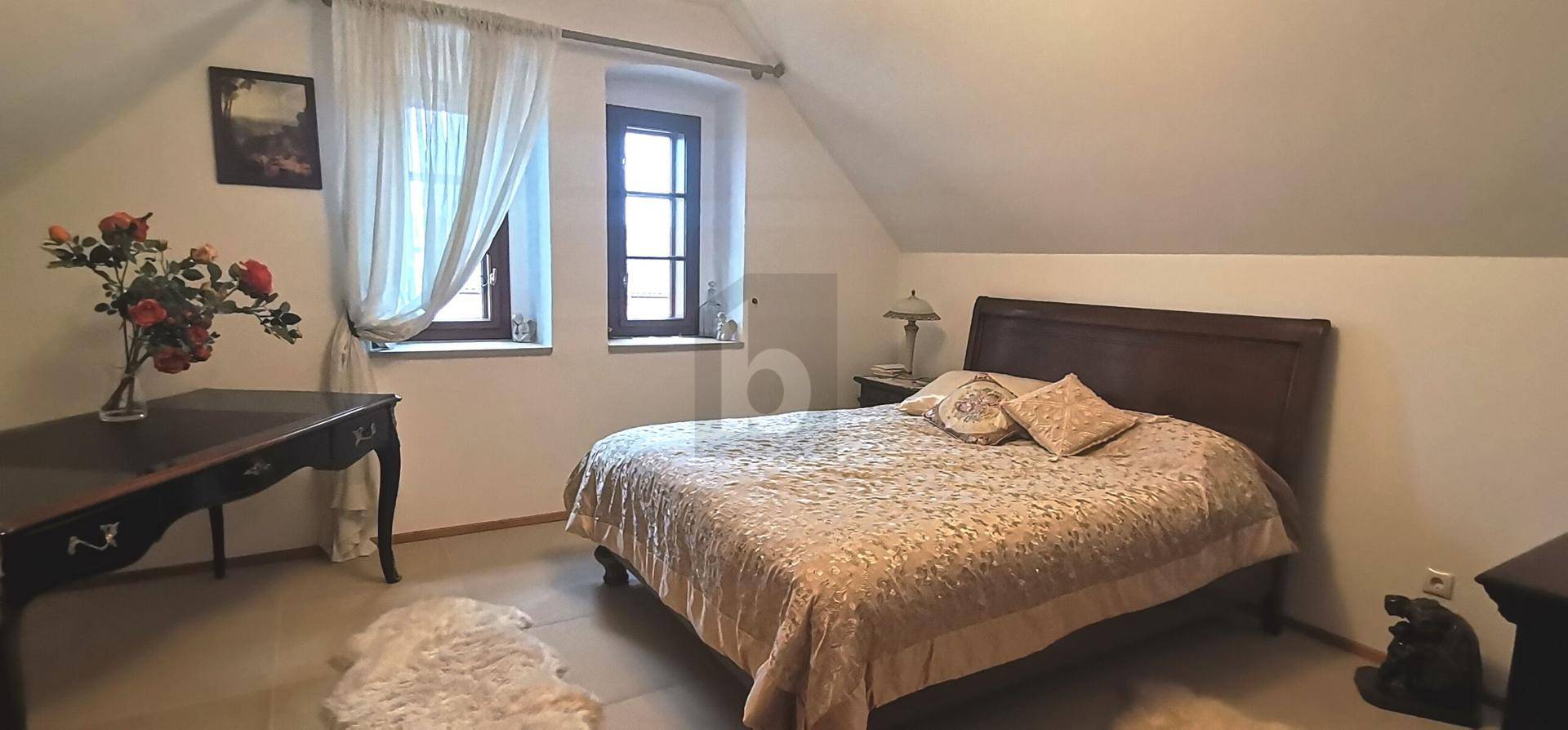 Helles Schlafzimmer im Dachgeschoss mit Doppelbett, zwei Fenstern und schrägen Decken.