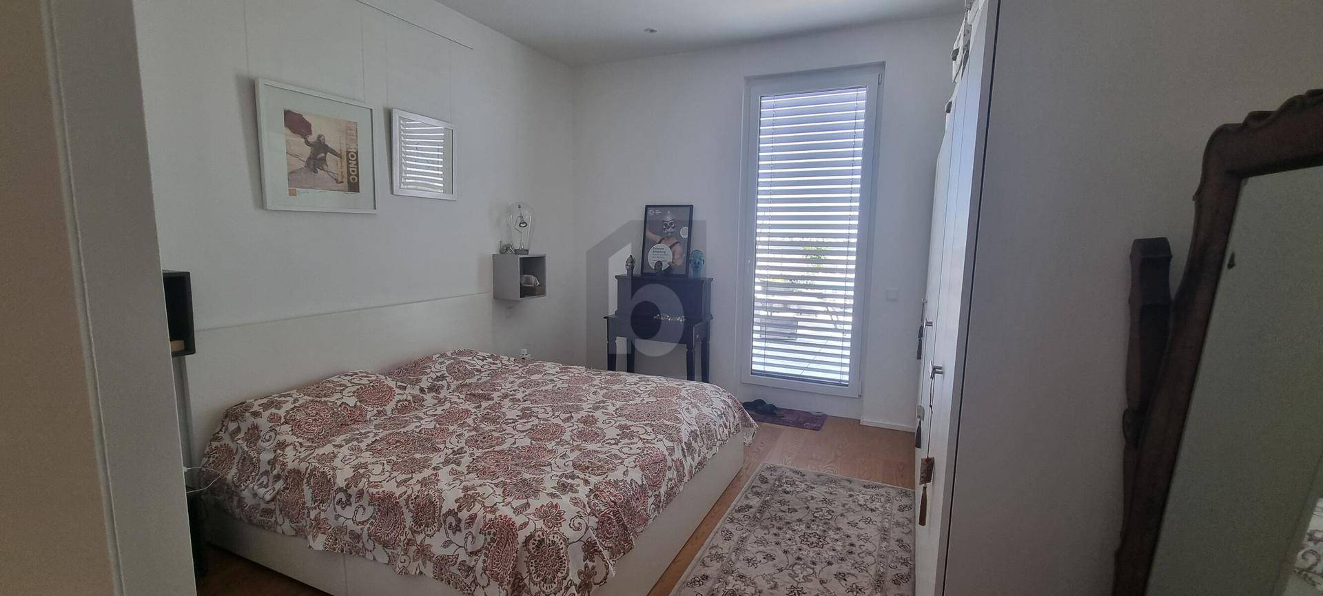 Gemütliches Schlafzimmer mit Doppelbett, Holzboden und Fenster mit Jalousien.