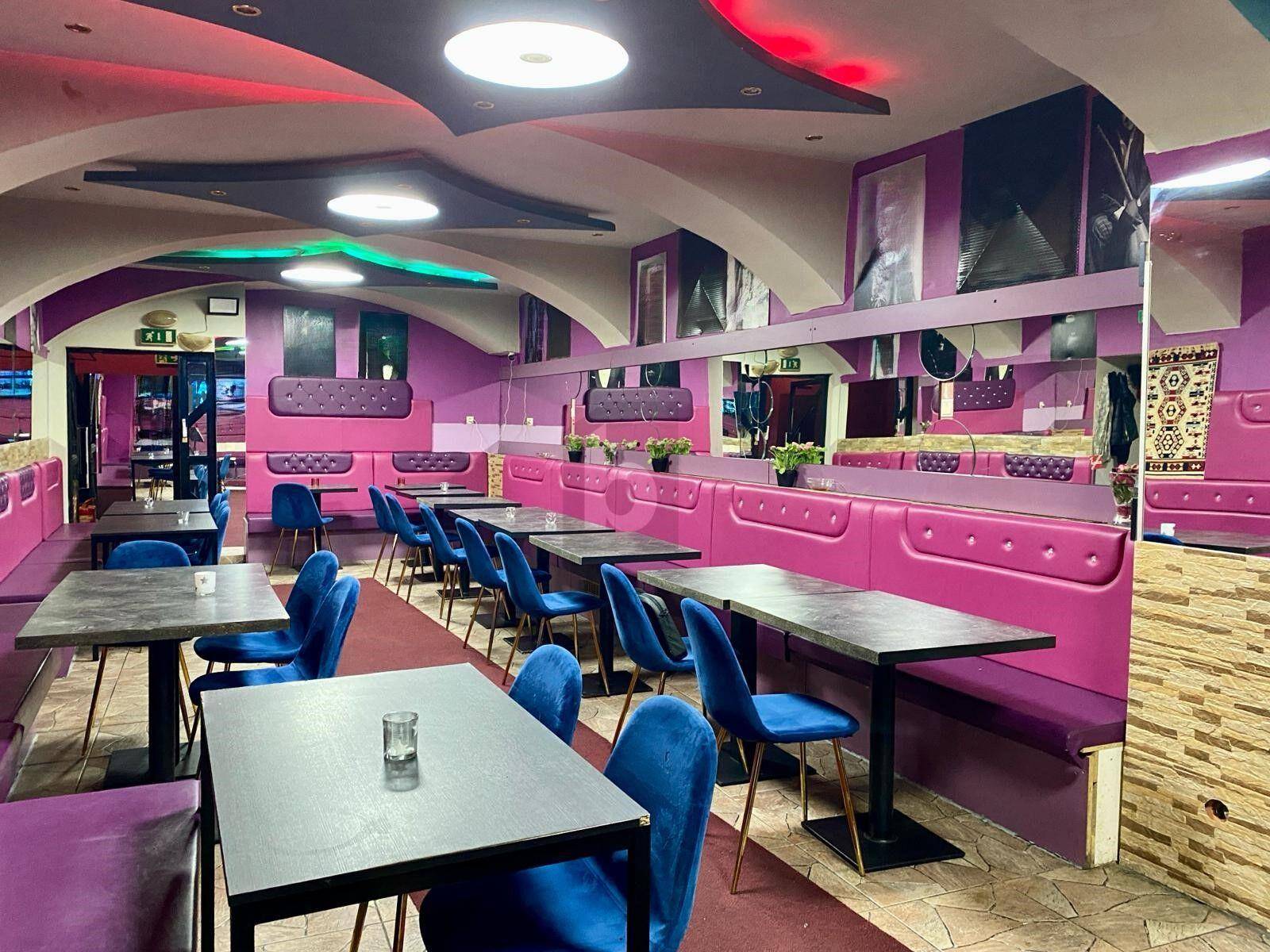 Geräumiger Restaurantbereich mit lebhafter Farbgestaltung, bequemen Sitzbänken und dekorativen Spiegeln.