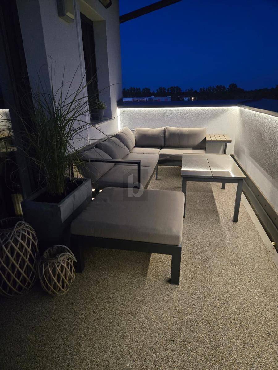 Beleuchtete Dachterrasse bei Nacht mit bequemen Loungemöbeln und einem ruhigen Blick auf das Wasser.