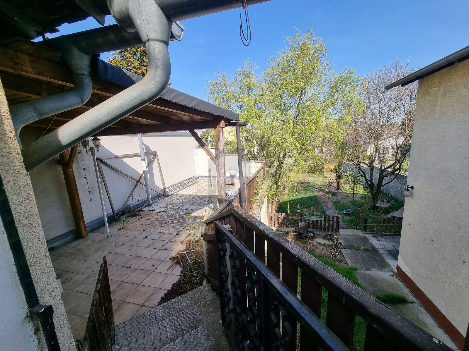 Überdachte Terrasse mit Treppenzugang zum Garten und Blick ins Grüne.