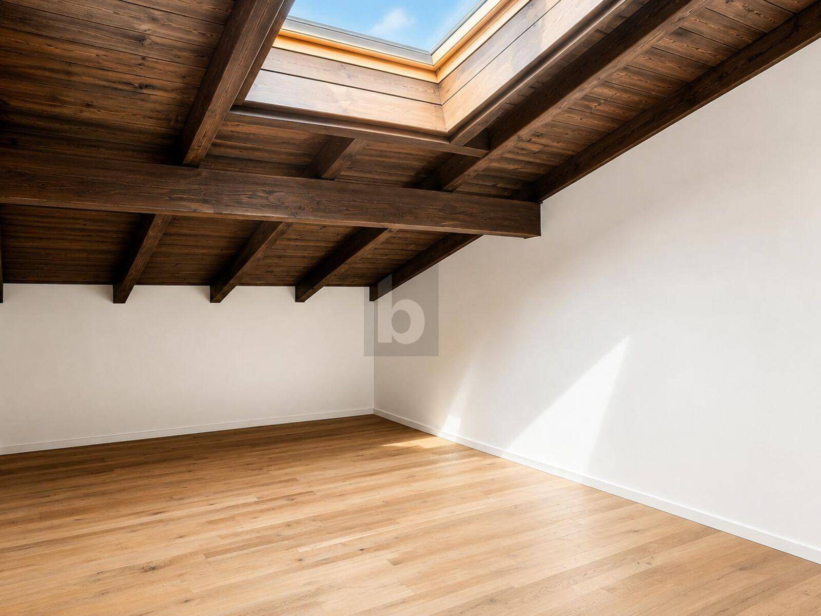 Heller Raum mit Holzbalkendecke und großem Dachfenster für viel Tageslicht.
