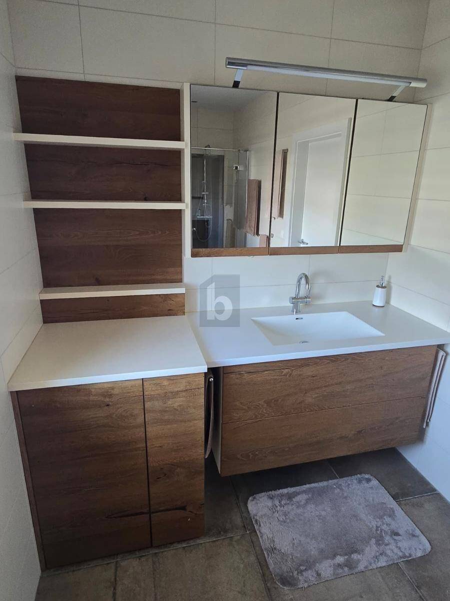 Modernes Badezimmer mit einem Holzwaschtisch, integriertem Waschbecken und einem Spiegelschrank.