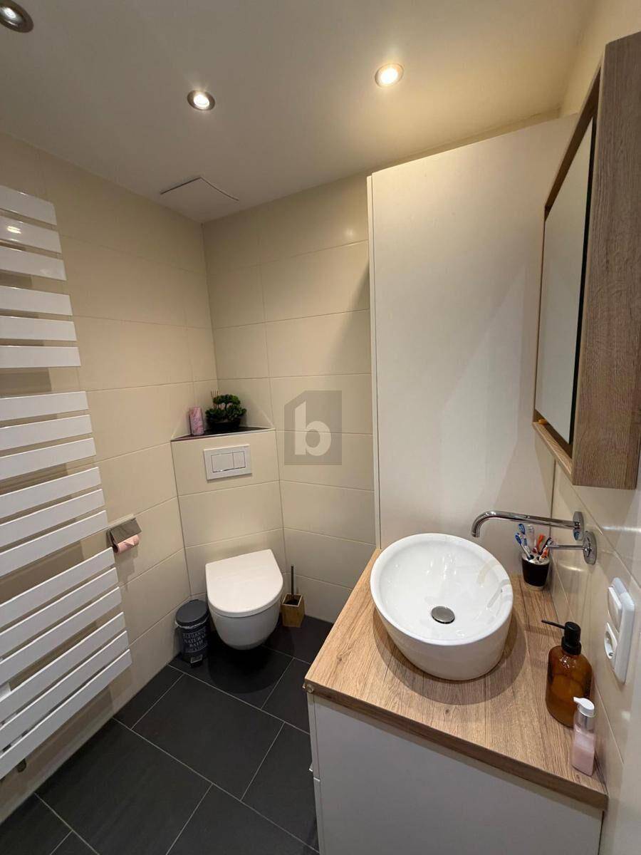 Modernes Badezimmer mit Wand-WC, Aufsatzwaschbecken und beheiztem Handtuchhalter.