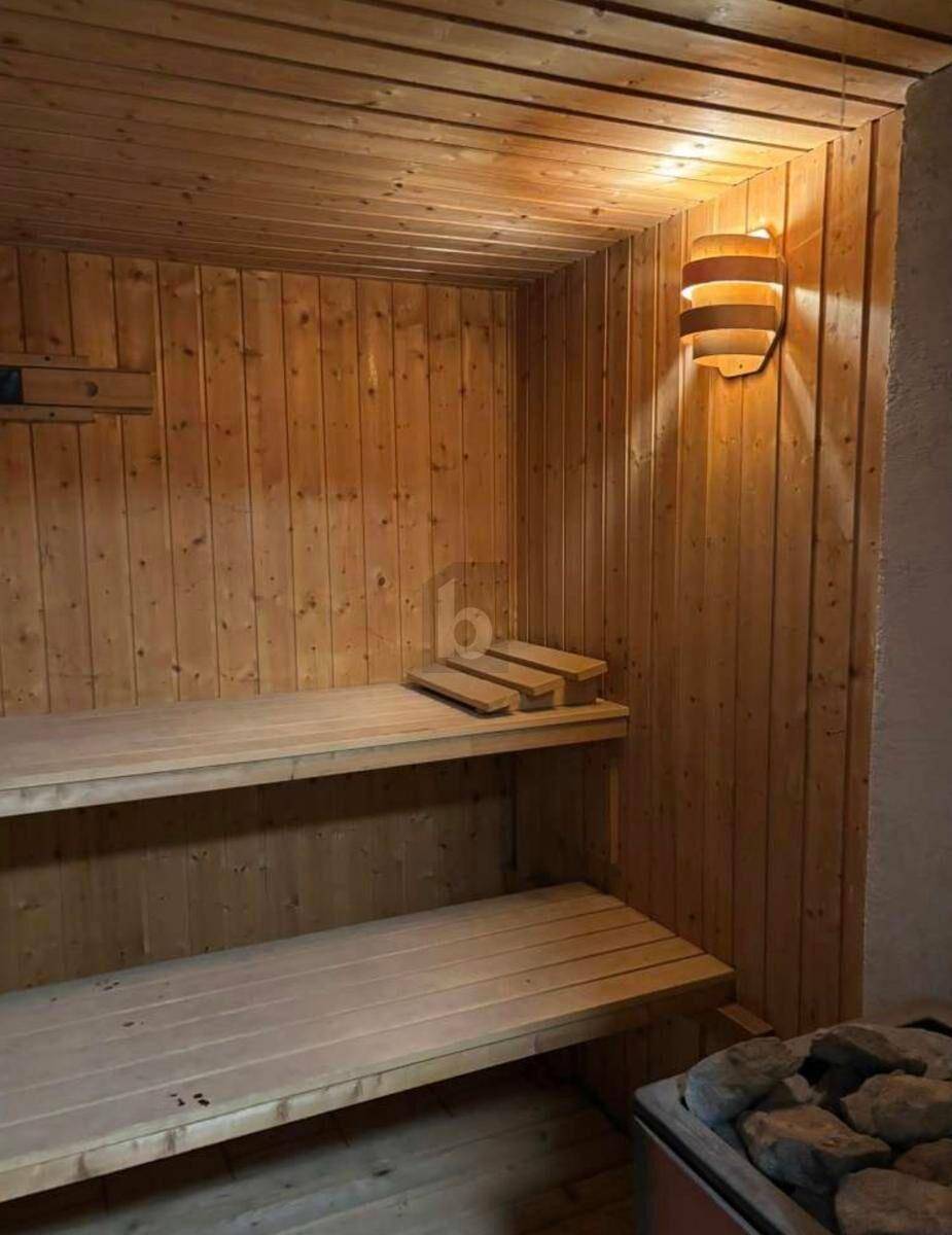 Helle Holzsauna mit mehreren Bänken und traditionellem Saunaofen für Entspannung.