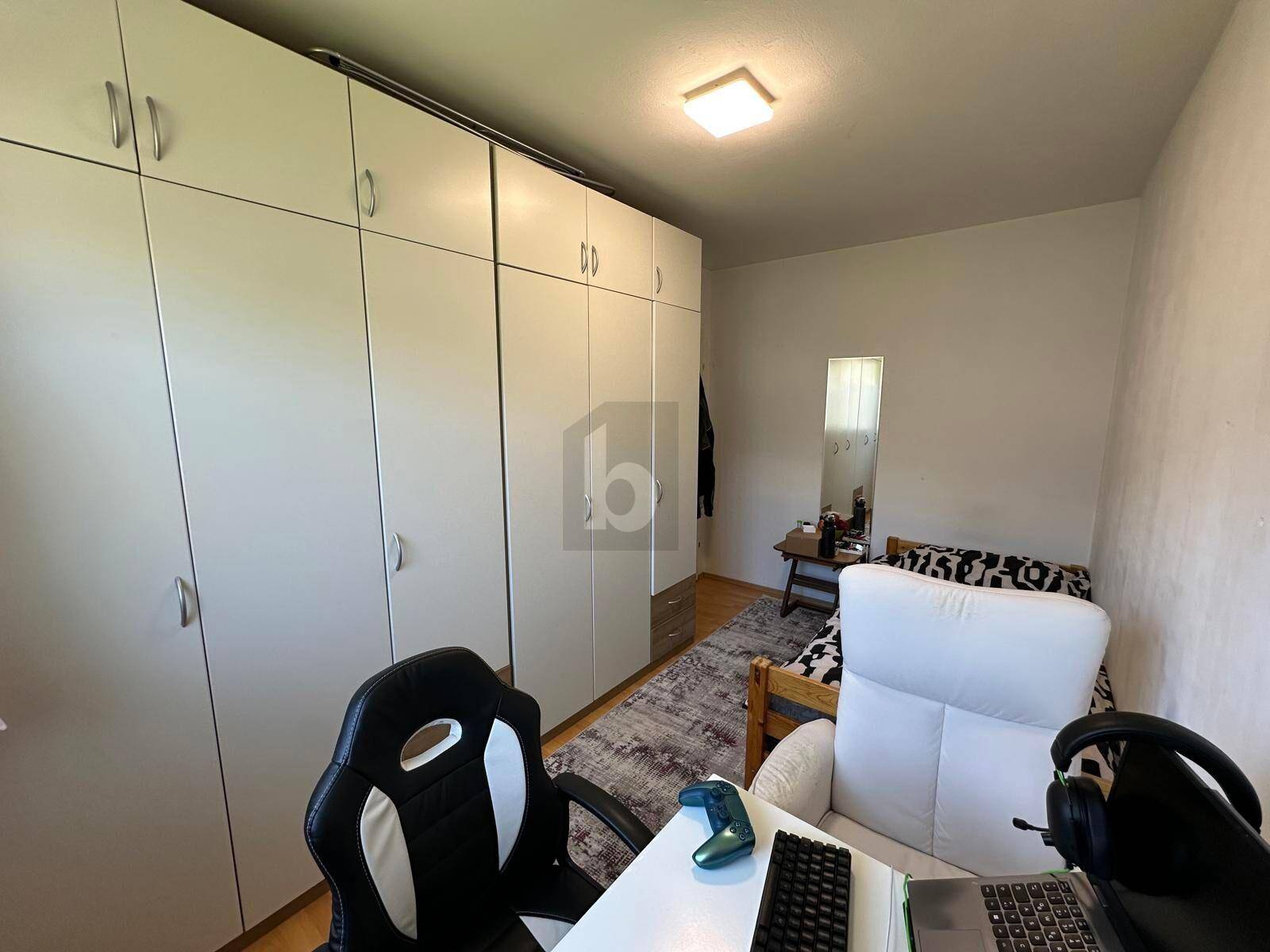Funktionales Schlafzimmer mit geräumigem Kleiderschrank, Schreibtisch und Einzelbett.