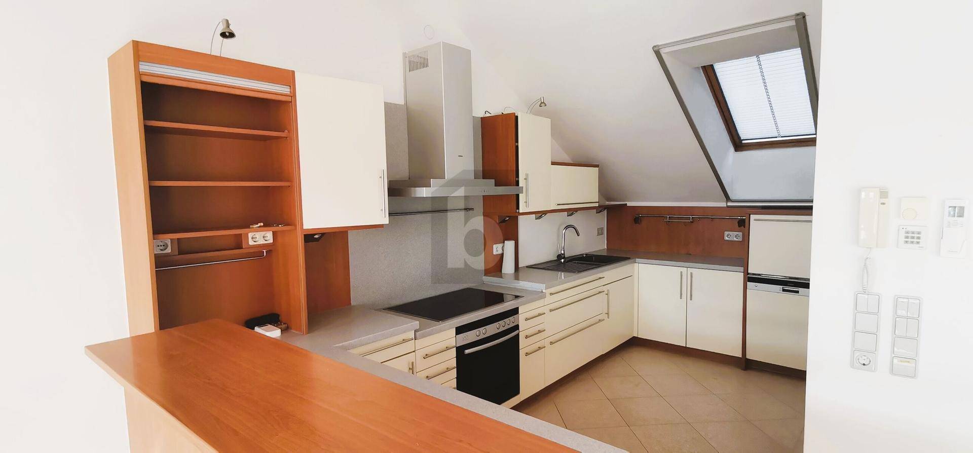 Funktionale Küche im Dachgeschoss mit hellen Schränken, integrierten Geräten und Dachfenster.