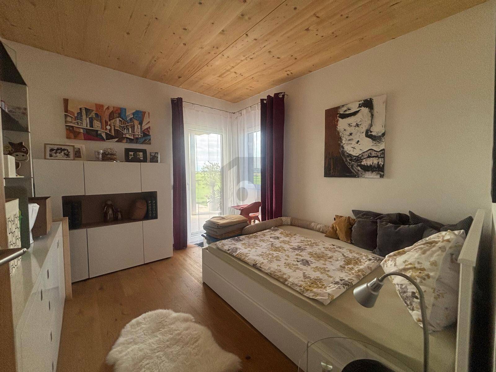 Gemütliches Schlafzimmer mit Holzbalkendecke, Holzboden und Zugang zum Außenbereich.