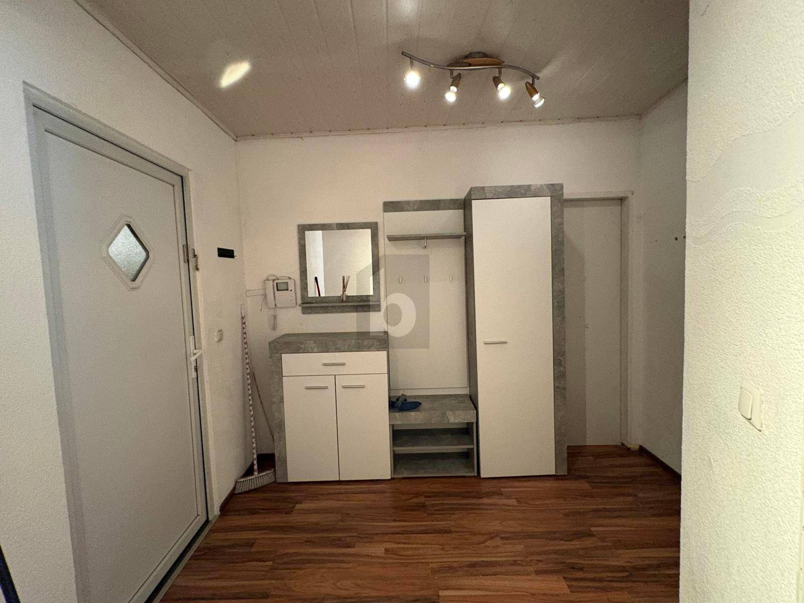 Heller Eingangsbereich mit Holzboden, Garderobe und praktischem Schuhschrank.