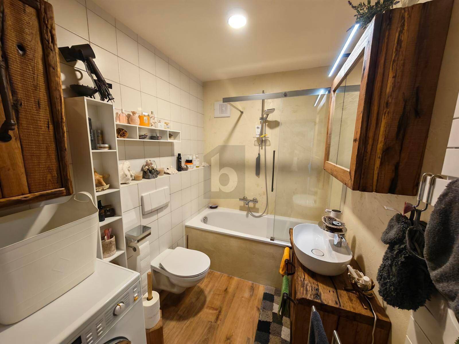 Badezimmer mit Badewanne, Duschbereich und Waschmaschine.