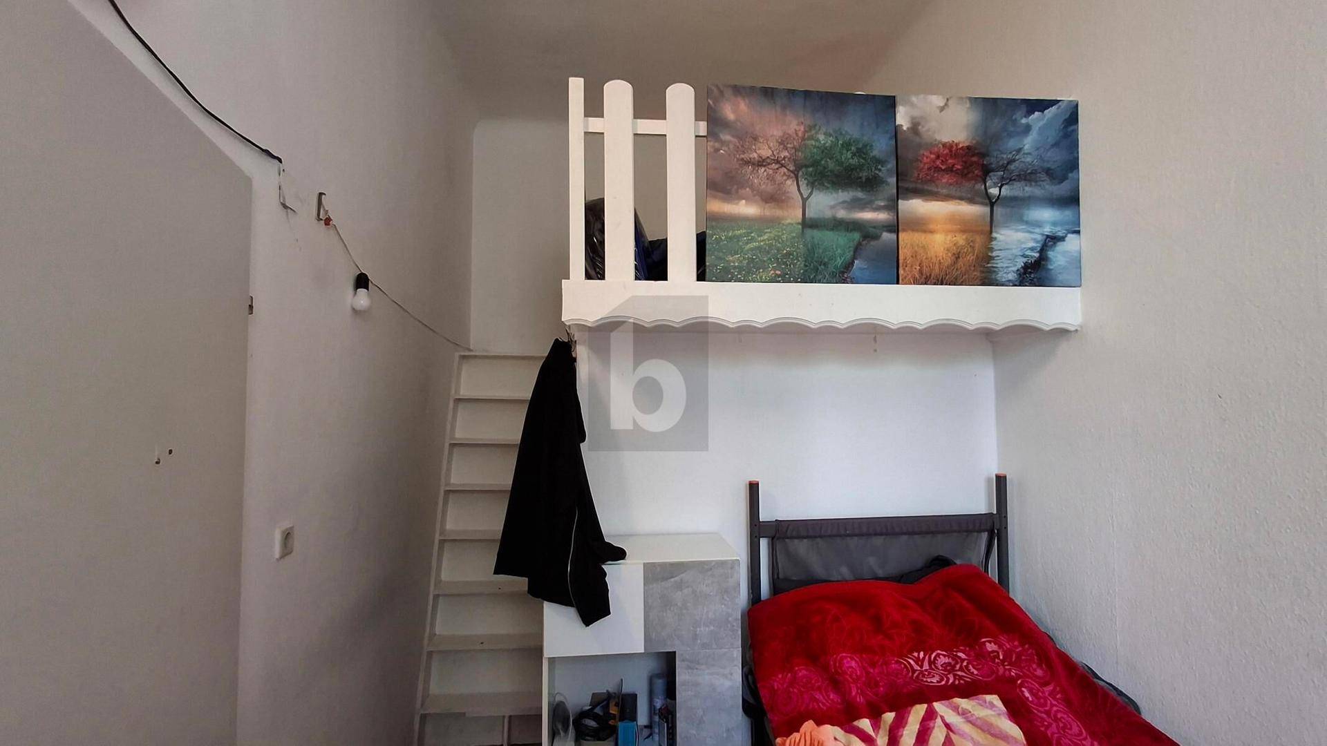 Schlafzimmer mit Hochbett-Struktur und Leiter, dekoriert mit Wandbildern.