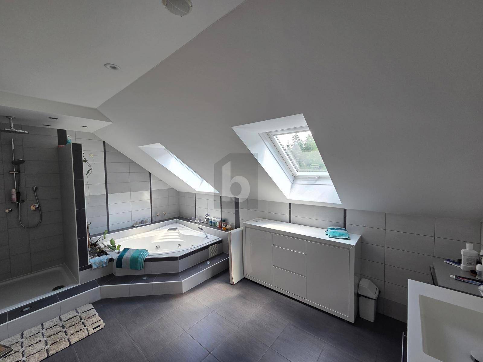 Modernes Badezimmer im Dachgeschoss mit Whirlpool, begehbarer Dusche und hellen Dachfenstern.