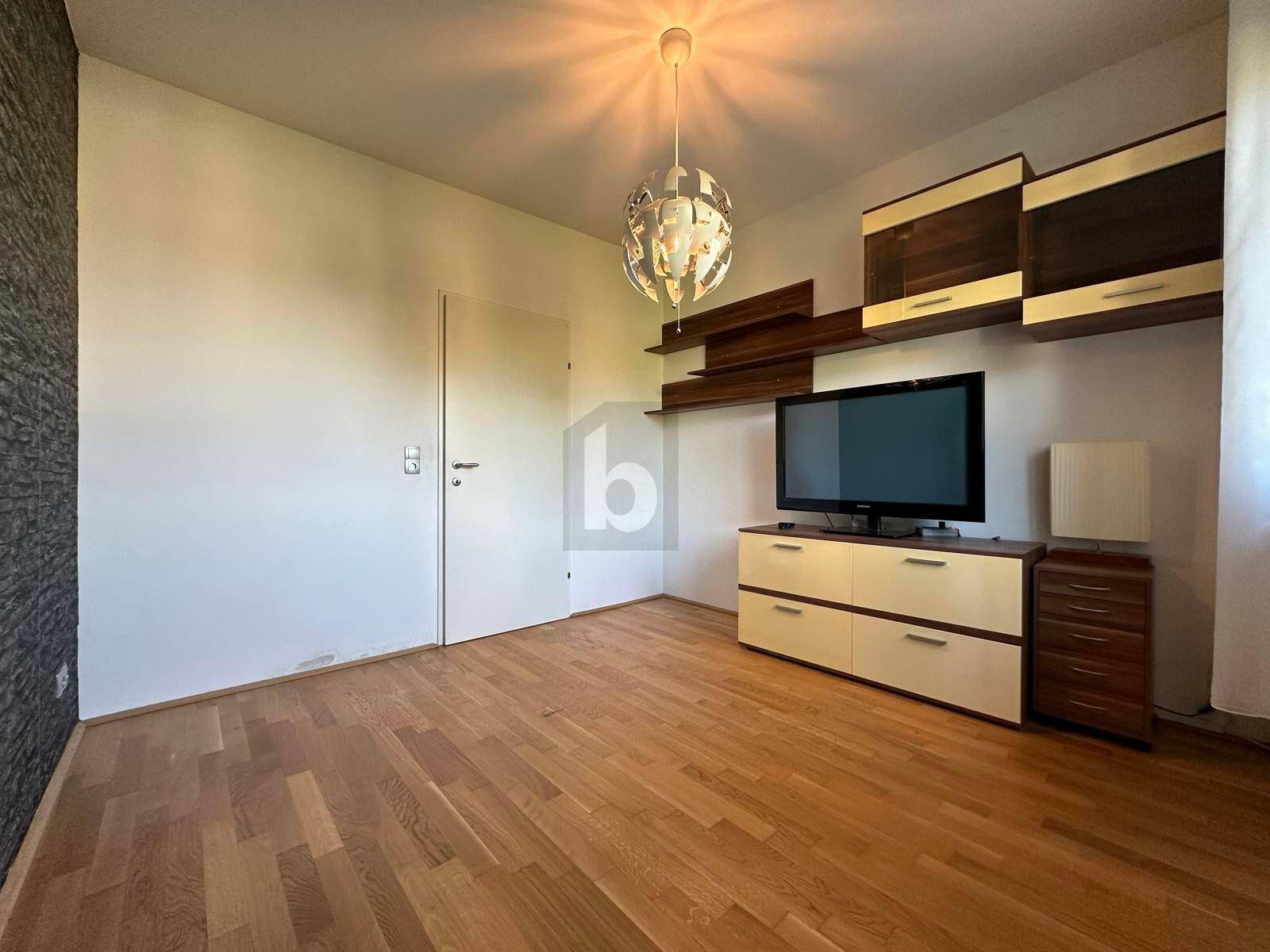 Gemütlicher Wohnraum mit Holzboden und einem modernen TV-Möbel mit Regalen.