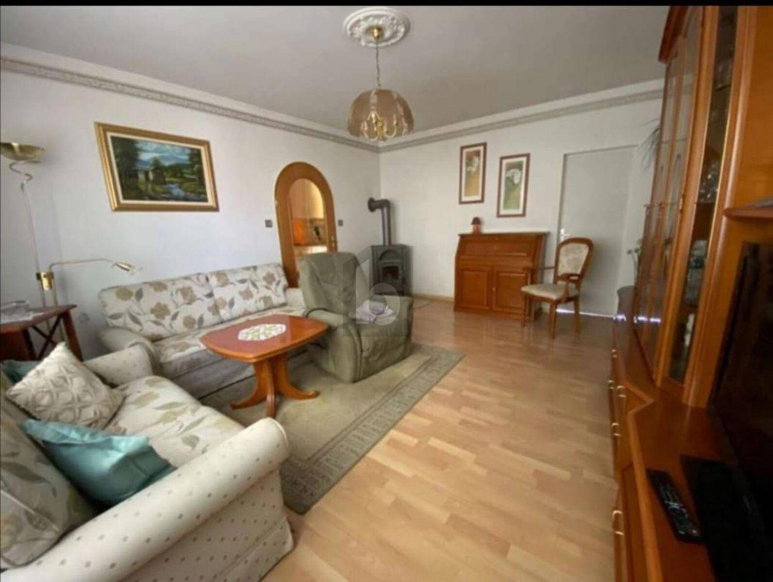 Gemütliches Wohnzimmer mit Holzboden, Kaminofen und traditionellen Möbeln.