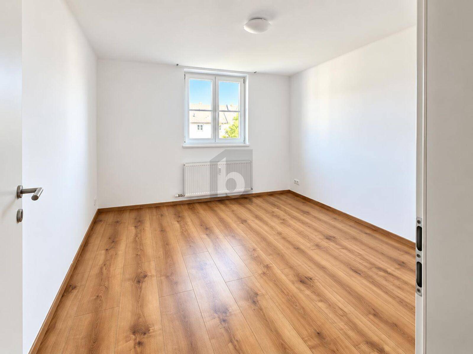 Helles Zimmer mit Laminatboden und großem Fenster, ideal als Schlaf- oder Arbeitszimmer.