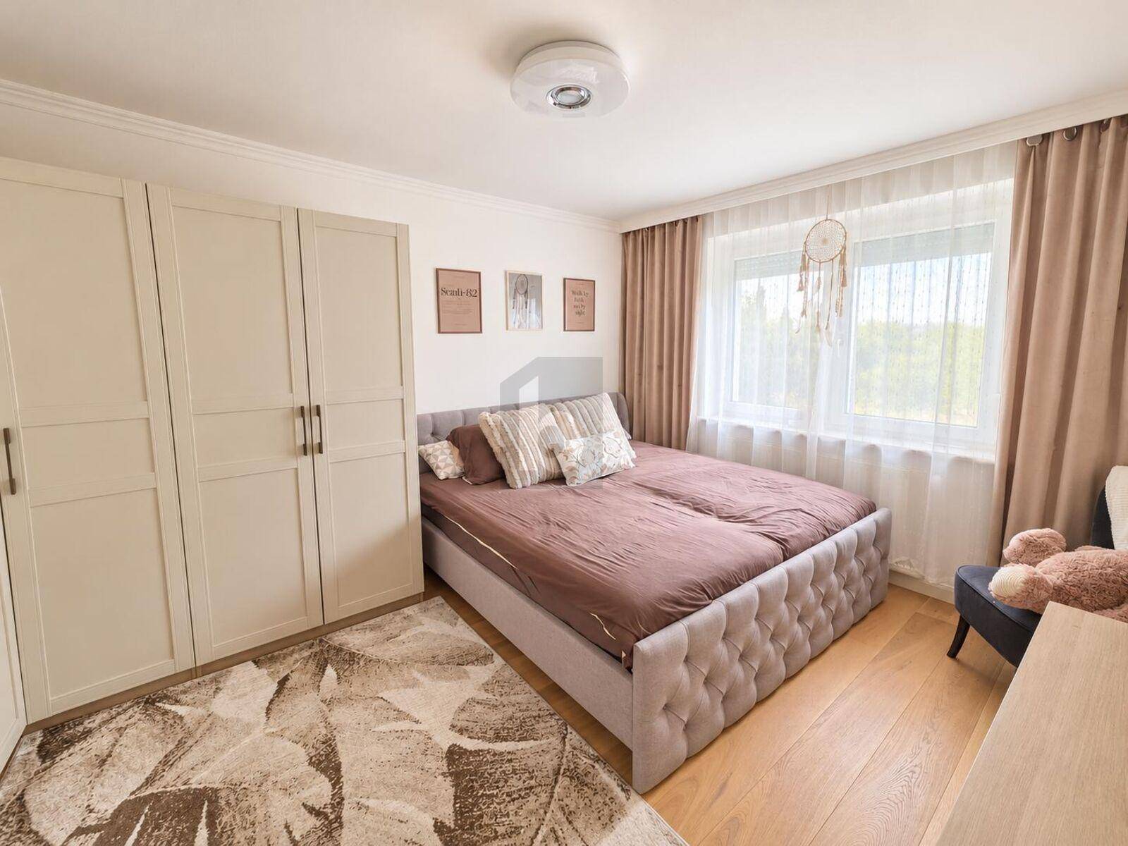 Gemütliches Schlafzimmer mit Doppelbett, Kleiderschrank und großen Fenstern für viel natürliches Licht.