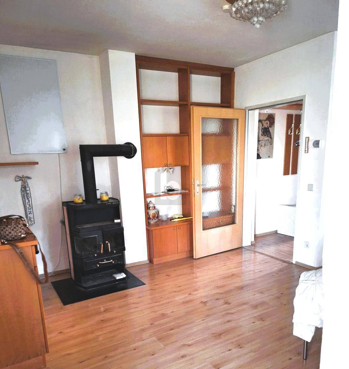 Gemütliches Wohnzimmer mit Holzofen, Holzboden und integriertem Regal.