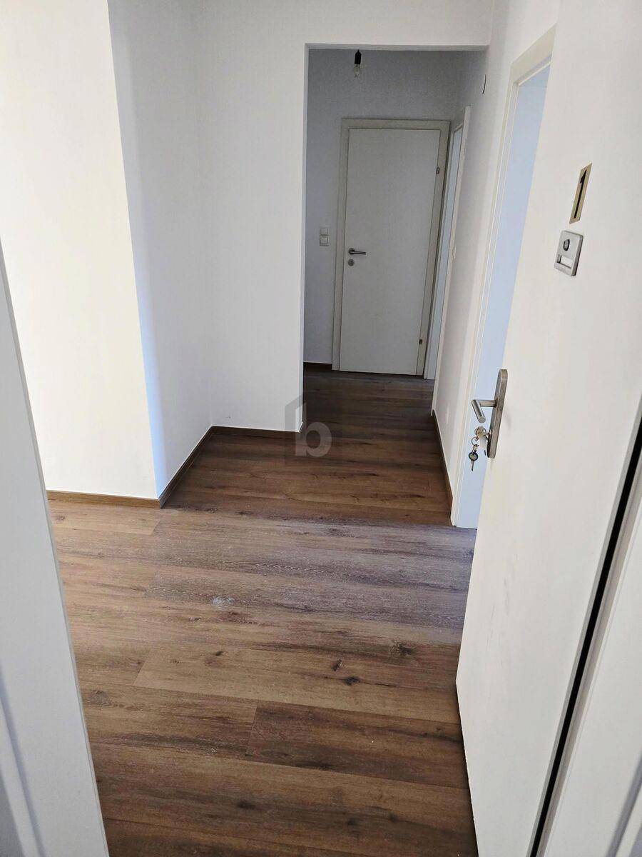 Heller Flur mit Laminatboden und weißen Türen, der zu weiteren Räumen führt.