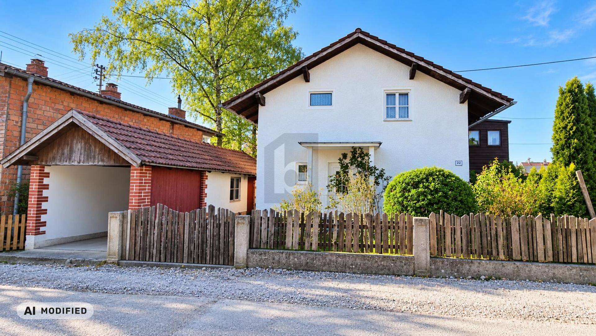 Einfamilienhaus mit Garage und Holzzaun an der Straße gelegen.