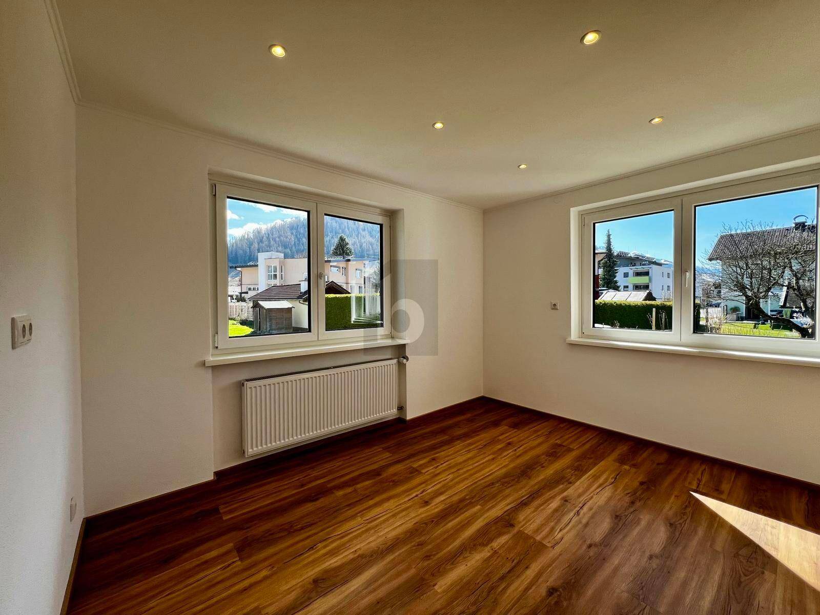Heller Raum mit Holzfußboden, Einbaustrahlern und Blick auf die umliegende Bebauung.