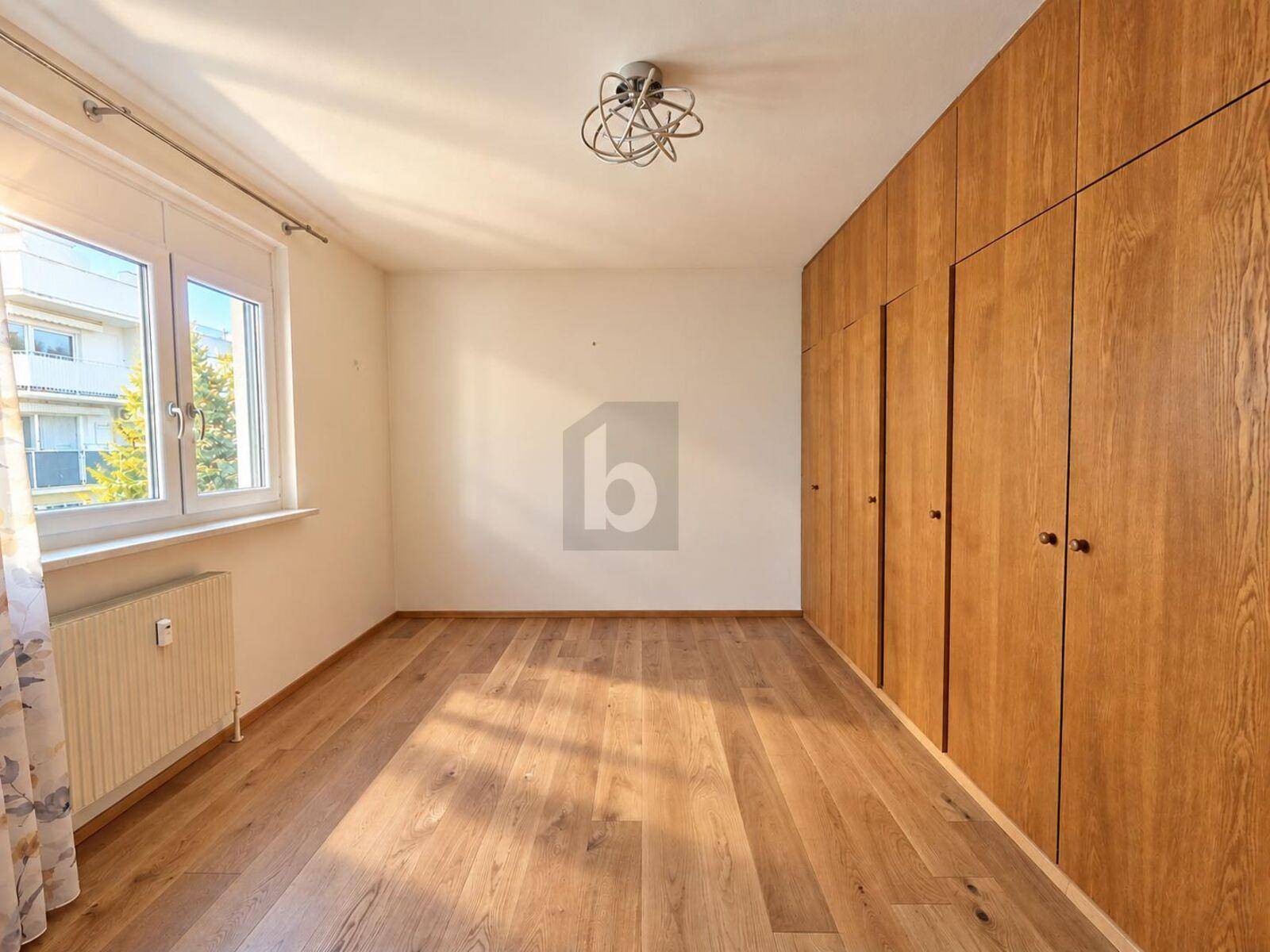 Helles Schlafzimmer mit Holzboden und großen Einbauschränken entlang einer Wand.