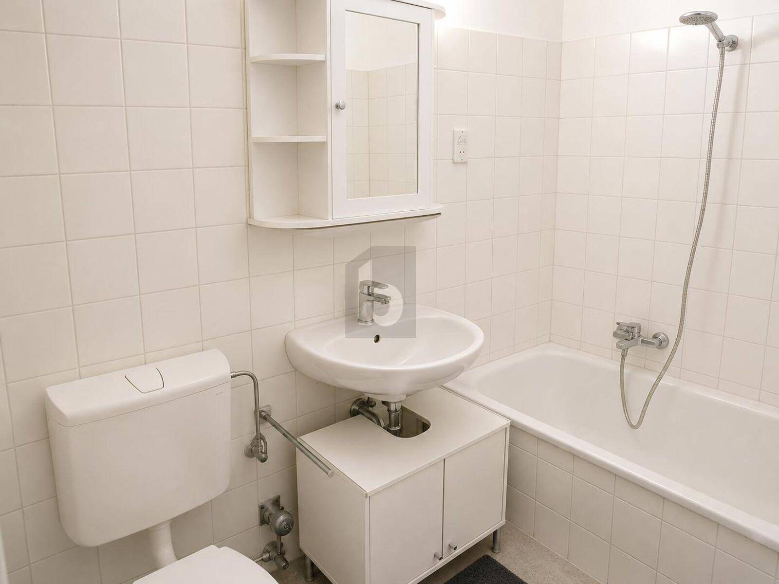Funktionales Badezimmer mit Badewanne, Waschbecken, Toilette und weißen Fliesen.