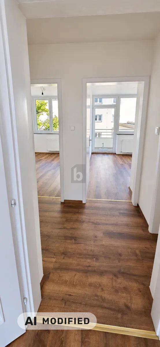 Heller Flur mit Holzboden und Durchgängen zu weiteren Räumen mit großen Fenstern.